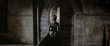 Movie still from “The Lion in Winter” (1968), directed by Anthony Harvey – A woman in a green dress standing in front of an arched doorway; Wide shot, High angle