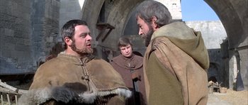 Movie still from “The Lion in Winter” (1968), directed by Anthony Harvey – A group of men standing next to each other on a street; Medium shot, Over the shoulder angle