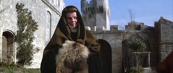 Movie still from “The Lion in Winter” (1968), directed by Anthony Harvey – A woman dressed in medieval garb standing in front of a castle; Medium shot, Low angle