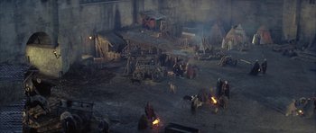 Movie still from “The Lion in Winter” (1968), directed by Anthony Harvey – A group of people standing around a fire pit; Extreme Wide shot, High angle