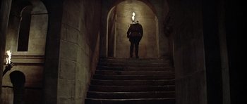 Movie still from “The Lion in Winter” (1968), directed by Anthony Harvey – A man standing on some steps in the dark; Wide shot, Low angle