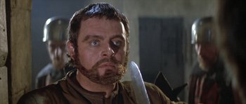 Movie still from “The Lion in Winter” (1968), directed by Anthony Harvey – A person with a beard holding a knife; Close Up shot, Low angle