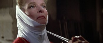 Movie still from “The Lion in Winter” (1968), directed by Anthony Harvey – A woman wearing a bandage is holding a pair of scissors; Close Up shot, Low angle