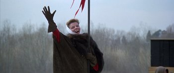 Movie still from “The Lion in Winter” (1968), directed by Anthony Harvey – A woman in a fur coat holding onto a flag pole; Medium shot, Low angle