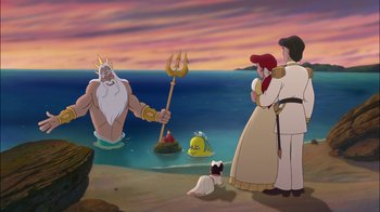 Movie still from “The Little Mermaid II: Return to the Sea” (2000), directed by Bill Speers – A group of people standing on top of a sandy beach; Wide shot, Over the shoulder angle