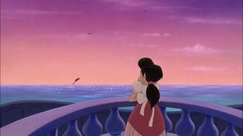 Movie still from “The Little Mermaid II: Return to the Sea” (2000), directed by Bill Speers – A woman standing on a balcony looking out at the ocean; Extreme Wide shot, Over the shoulder angle
