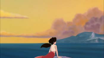 Movie still from “The Little Mermaid II: Return to the Sea” (2000), directed by Bill Speers – A woman sitting on top of a surfboard in front of a body of water; Extreme Wide shot, Low angle