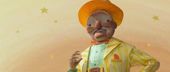 Movie still from “The Little Prince” (2015), directed by Mark Osborne – A statue of a man wearing a yellow hat; Medium shot, Low angle