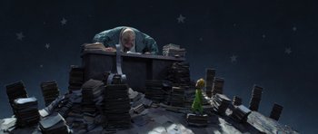 Movie still from “The Little Prince” (2015), directed by Mark Osborne – A man standing over a pile of papers next to a little green man; Wide shot, Low angle