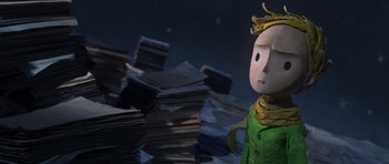 Movie still from “The Little Prince” (2015), directed by Mark Osborne – A toy character is standing in front of a pile of papers; Medium shot, Over the shoulder angle