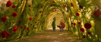 Movie still from “The Little Prince” (2015), directed by Mark Osborne – A child in a green outfit and a fake animal in a tunnel; Wide shot, High angle