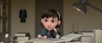 Movie still from “The Little Prince” (2015), directed by Mark Osborne – An animated girl is sitting at a table with a book and pen; Medium shot, High angle