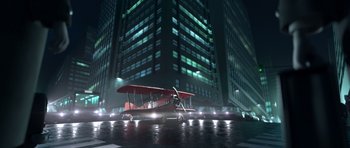 Movie still from “The Little Prince” (2015), directed by Mark Osborne – A red biplane parked in front of a tall building at night; Extreme Wide shot, Low angle