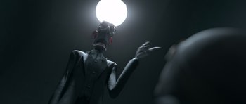 Movie still from “The Little Prince” (2015), directed by Mark Osborne – A man in a suit and tie is standing in front of a light; Medium shot, Low angle