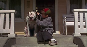 Movie still from “The Little Rascals” (1994), directed by Penelope Spheeris – A boy sitting on the steps of a house petting a dog; Close Up shot, Over the shoulder angle