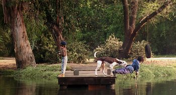 Movie still from “The Little Rascals” (1994), directed by Penelope Spheeris – A boy and a dog on a dock in the water; Wide shot, High angle