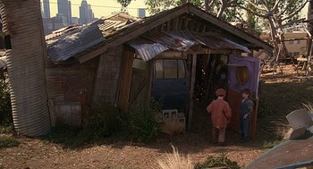 Movie still from “The Little Rascals” (1994), directed by Penelope Spheeris – A person standing in front of an old shack; Wide shot, High angle