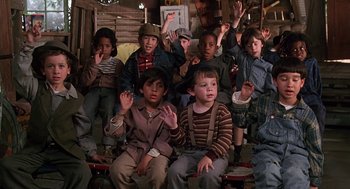 Movie still from “The Little Rascals” (1994), directed by Penelope Spheeris – A group of children sitting in front of a wooden wall; Medium shot, High angle