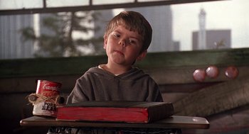 Movie still from “The Little Rascals” (1994), directed by Penelope Spheeris – A young boy sitting at a table with a book in front of him; Close Up shot, Low angle