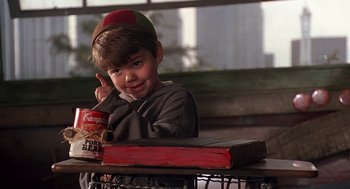 Movie still from “The Little Rascals” (1994), directed by Penelope Spheeris – A young boy sitting at a table with a box of cereal; Close Up shot, High angle