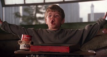 Movie still from “The Little Rascals” (1994), directed by Penelope Spheeris – A young boy sitting in front of a book; Medium shot, Low angle