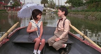 Movie still from “The Little Rascals” (1994), directed by Penelope Spheeris – A young boy and girl sitting on a boat; Medium shot, High angle