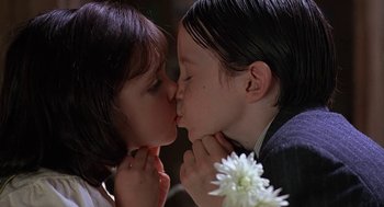 Movie still from “The Little Rascals” (1994), directed by Penelope Spheeris – Two young children kissing each other with flowers in front of them; Close Up shot, Low angle