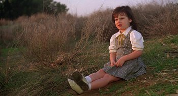 Movie still from “The Little Rascals” (1994), directed by Penelope Spheeris – A little girl sitting on the ground in the grass; Medium shot, High angle