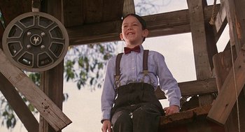 Movie still from “The Little Rascals” (1994), directed by Penelope Spheeris – A young boy wearing suspenders and a bow tie; Medium shot, Low angle