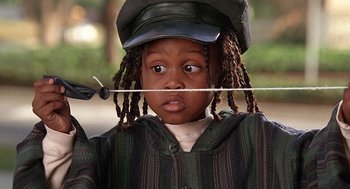 Movie still from “The Little Rascals” (1994), directed by Penelope Spheeris – A young child wearing a hat and holding a stick in his mouth; Close Up shot, Low angle