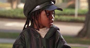 Movie still from “The Little Rascals” (1994), directed by Penelope Spheeris – A little boy with long braids wearing a hat; Close Up shot, High angle