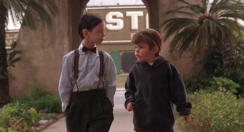 Movie still from “The Little Rascals” (1994), directed by Penelope Spheeris – Two young boys standing next to each other on a sidewalk; Medium shot, Low angle