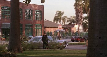 Movie still from “The Little Rascals” (1994), directed by Penelope Spheeris – A man standing next to a car on the side of the road; Extreme Wide shot, Over the shoulder angle