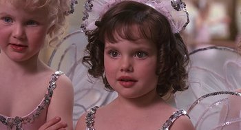 Movie still from “The Little Rascals” (1994), directed by Penelope Spheeris – A little girl in a silver dress and a pink bow; Close Up shot, High angle
