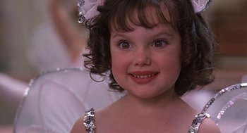 A little girl in a white dress with a bow in her hair