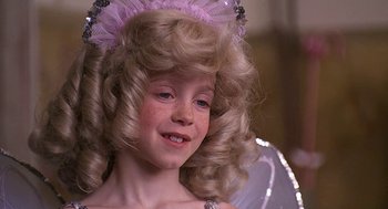 Movie still from “The Little Rascals” (1994), directed by Penelope Spheeris – A young girl with blonde hair wearing a pink and white costume; Close Up shot, Over the shoulder angle