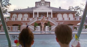 Movie still from “The Little Rascals” (1994), directed by Penelope Spheeris – A man standing on a surfboard in a swimming pool; Extreme Wide shot, Low angle