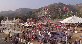 Movie still from “The Little Rascals” (1994), directed by Penelope Spheeris – A crowd of people standing around a carnival ride; Extreme Wide shot, High angle
