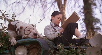 Movie still from “The Little Rascals” (1994), directed by Penelope Spheeris – A boy sitting on top of a dog reading a book; Medium shot, Low angle