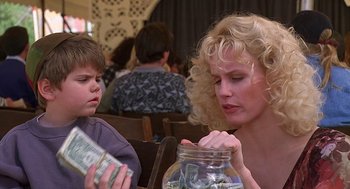 Movie still from “The Little Rascals” (1994), directed by Penelope Spheeris – A woman and a boy sitting in front of a jar; Close Up shot, Over the shoulder angle