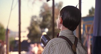 Movie still from “The Little Rascals” (1994), directed by Penelope Spheeris – A person holding a microphone in his hands; Close Up shot, Over the shoulder angle
