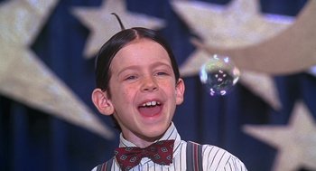 Movie still from “The Little Rascals” (1994), directed by Penelope Spheeris – A young boy with a bow tie is smiling; Close Up shot, Low angle