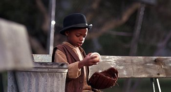 Movie still from “The Little Rascals” (1994), directed by Penelope Spheeris – A young boy wearing a hat and holding a baseball glove; Close Up shot, Low angle