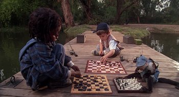 Movie still from “The Little Rascals” (1994), directed by Penelope Spheeris – Two young children playing a game of chess on a dock; Wide shot, High angle