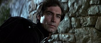 Movie still from “The Living Daylights” (1987), directed by John Glen – A man's face in front of a stone wall; Close Up shot, Low angle