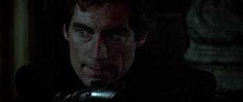 Movie still from “The Living Daylights” (1987), directed by John Glen – A person with a gun in a dark room; Close Up shot, Over the shoulder angle