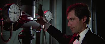 Movie still from “The Living Daylights” (1987), directed by John Glen – A man is holding on to a manometer; Close Up shot, Low angle