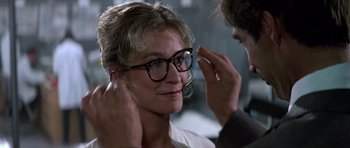 Movie still from “The Living Daylights” (1987), directed by John Glen – An older woman wearing a pair of eyeglasses; Close Up shot, Over the shoulder angle