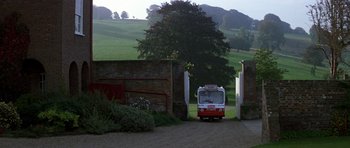 Movie still from “The Living Daylights” (1987), directed by John Glen – A red and white bus driving down a road; Extreme Wide shot, High angle