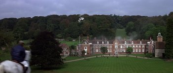 Movie still from “The Living Daylights” (1987), directed by John Glen – A helicopter is flying over a large green field; Extreme Wide shot, High angle